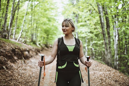 Portrait Of Smiling Female Hiker Enjoying Walking Through Forest