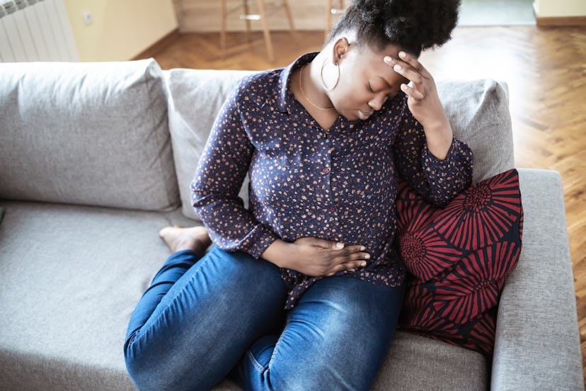 woman with stomach pain sitting on couch