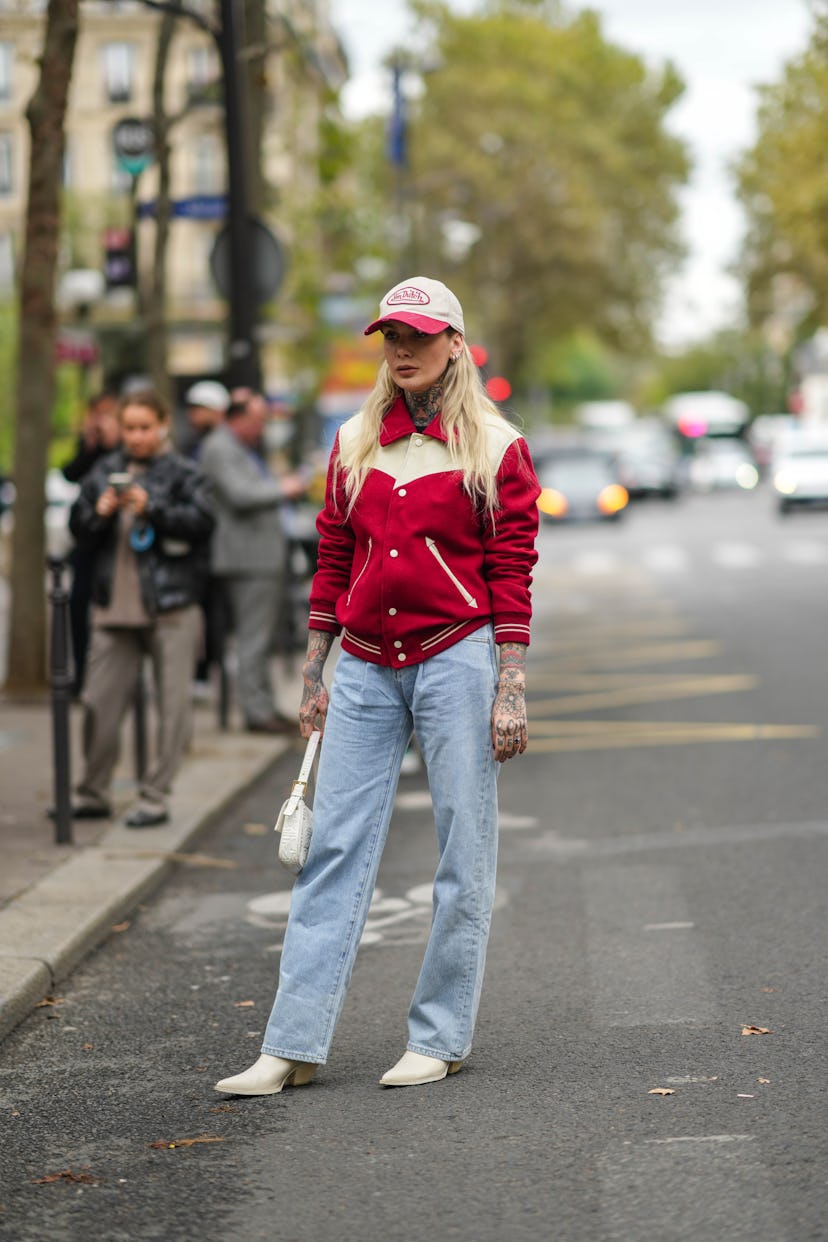 PARIS, FRANCE - OCTOBER 01: A guest wears a white and red ripped Von Dutch cap, silver earrings, a r...