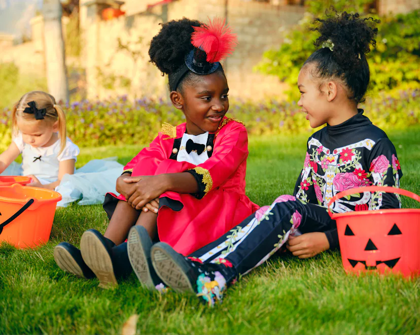 A diverse group of children, dressed in costumes, trick or treating in a residential USA neighborhoo...
