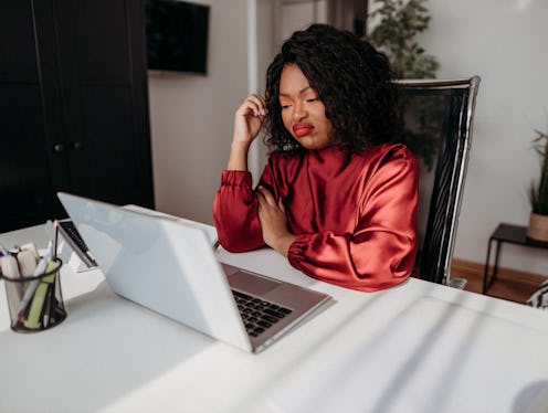 A woman purses her lips at her laptop, wondering how to delete facebook. Here's what happens when yo...