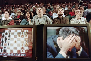Chess enthusiasts watch World Chess champion Garry Kasparov on a television monitor as he holds his ...