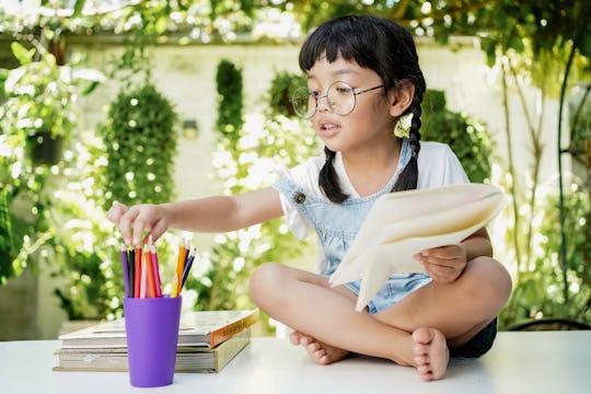 Asian student girl drawing and writing on the book for homework at home