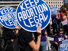 Women rights activists and advocates for abortion rights hold up signs as they gather at Freedom Pla...