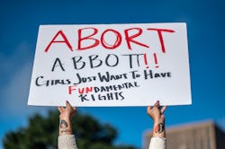 A woman holds a sign in reference to Texas Governor Greg Abbott as protesters take part in the Women...