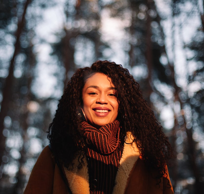 Young woman wearing coat in forest during November 2021, the best month for her zodiac sign.
