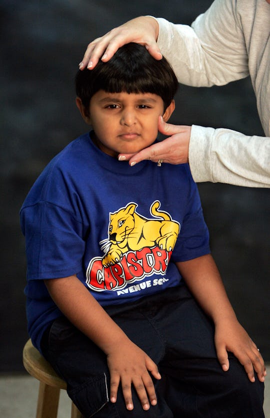 Joshua Baptista, a 1st grader, has his head posed into the proper position before being photographed...