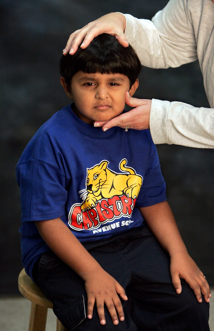 Joshua Baptista, a 1st grader, has his head posed into the proper position before being photographed...