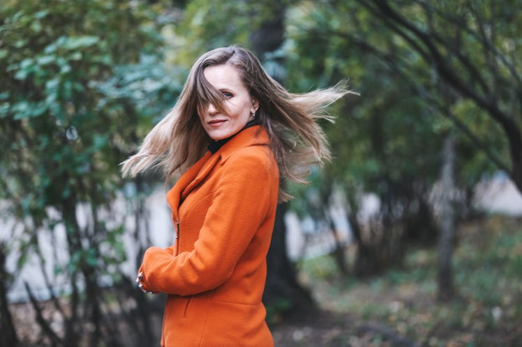 Young woman twirling in orange coat after reading her November 2021 monthly horoscope.