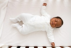 Baby sleeping on its back in a crib