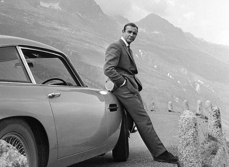 1964:  Actor Sean Connery poses as James Bond next to his Aston Martin DB5 in a scene from the Unite...