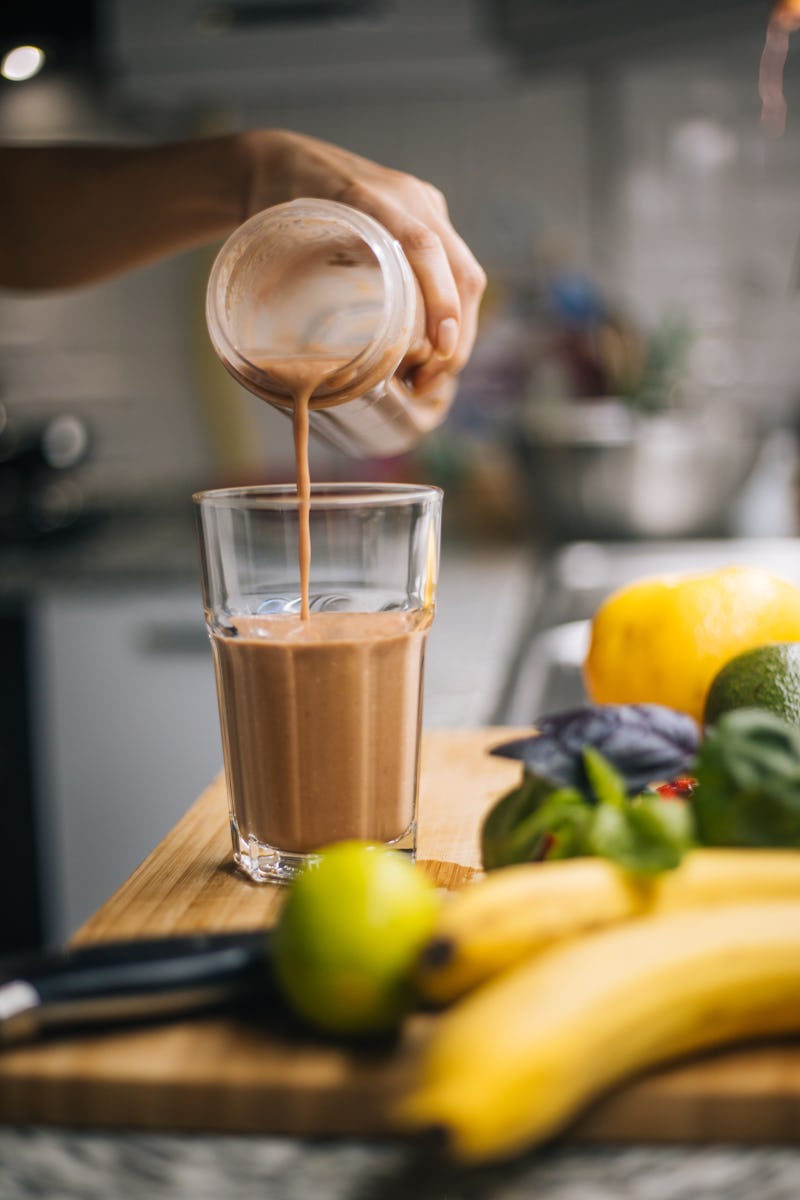 A woman prepares a smoothie using pre-workout powder. On TikTok, people are dry-scooping pre-workout...