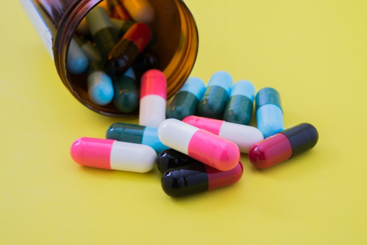 Medical pills spilling out of a toppled from pill bottle