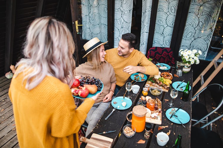 Friends enjoy a Friendsgiving feast on their back porch, for which they'll need Friendsgiving group ...