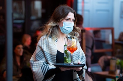 CARDIFF, WALES - APRIL 30: A woman wearing a face mask carries a tray of drinks at Pitch bar on Apri...