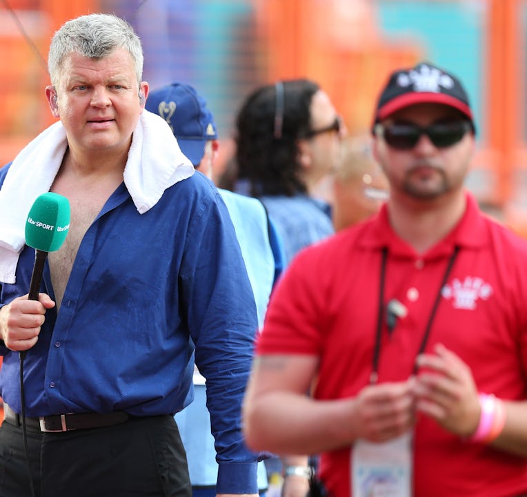 Adrian Chiles of ITV Sport unbuttons is shirt and walks around with a towel around his neck before b...