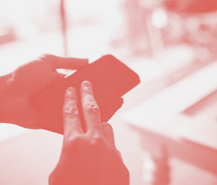 Cropped shot of an unrecognisable man wiping a smartphone with a cloth at home