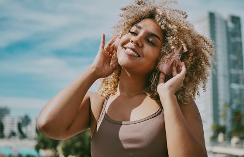 A woman with blonde natural hair listens to music. Here are the zodiac signs least affected by the N...