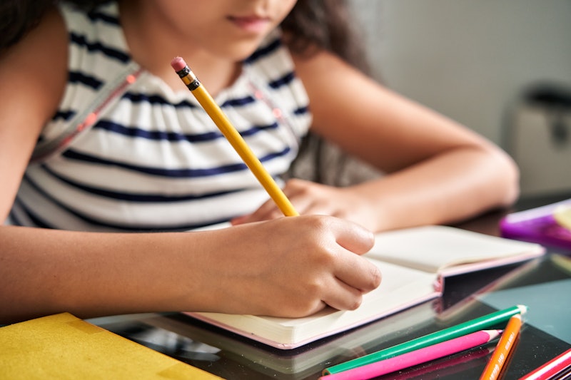 Home online schooling: Close up of little girl doing homework at home