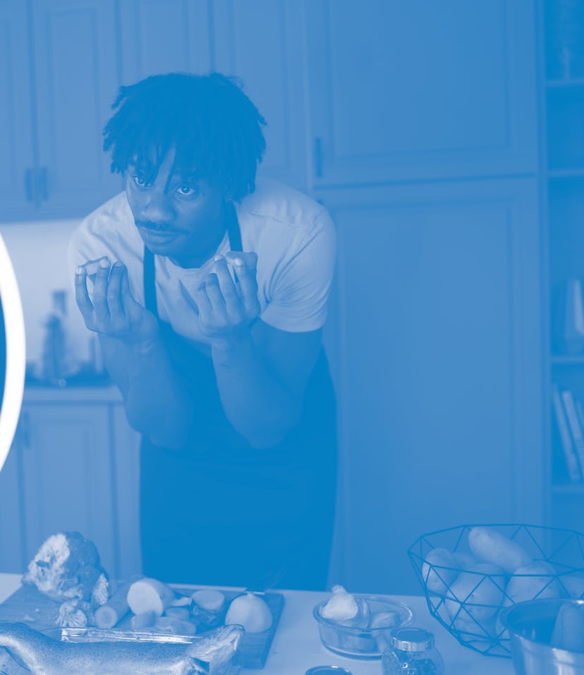 Using the fresh ingredients on the cutting board and table before him, an African-American chef is b...