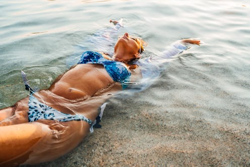 Young woman floating on her back on the sea. Here's your daily horoscope for November 12 2021.