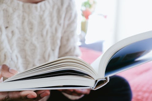 Close-up of unrecognizable black woman reading book while sitting on bed