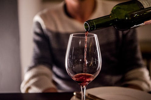 PRODUCTION - 03 October 2021, Bavaria, Munich: A woman pours wine into a glass at home. A man sits i...