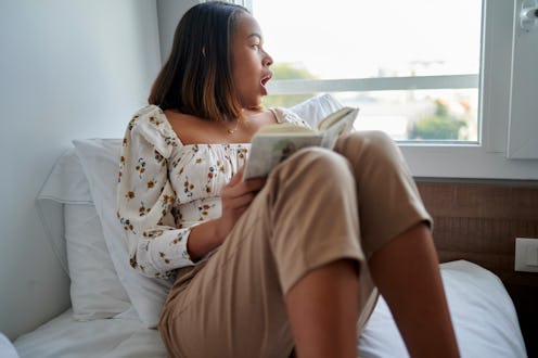 Woman with book in bed yawning