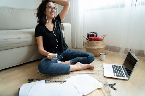 Young woman sitting on floor of her apartment with laptop and notes working