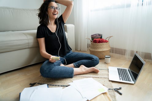 Young woman sitting on floor of her apartment with laptop and notes working