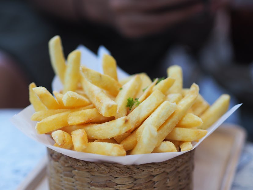 Closeup French fries, Potato chips Yellow crispy fries in wooden basket on white table, snack delici...