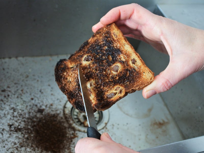 POV (point of view) of a person(female hands) holding and removing burnt from a toast with a kitchen...