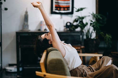 A woman stretches on a chair. Here's your daily horoscope for November 17 2021.