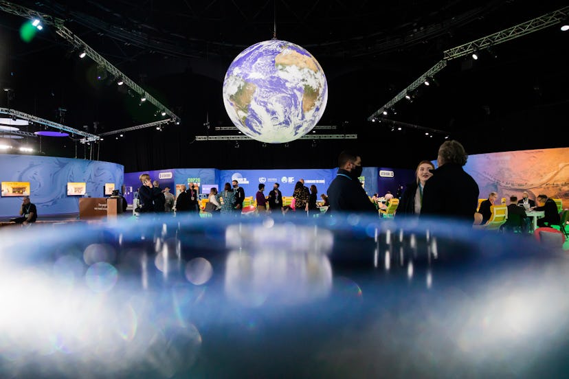 People are standing under a globe at the UN Climate Change Conference COP26. For two weeks in Glasgo...