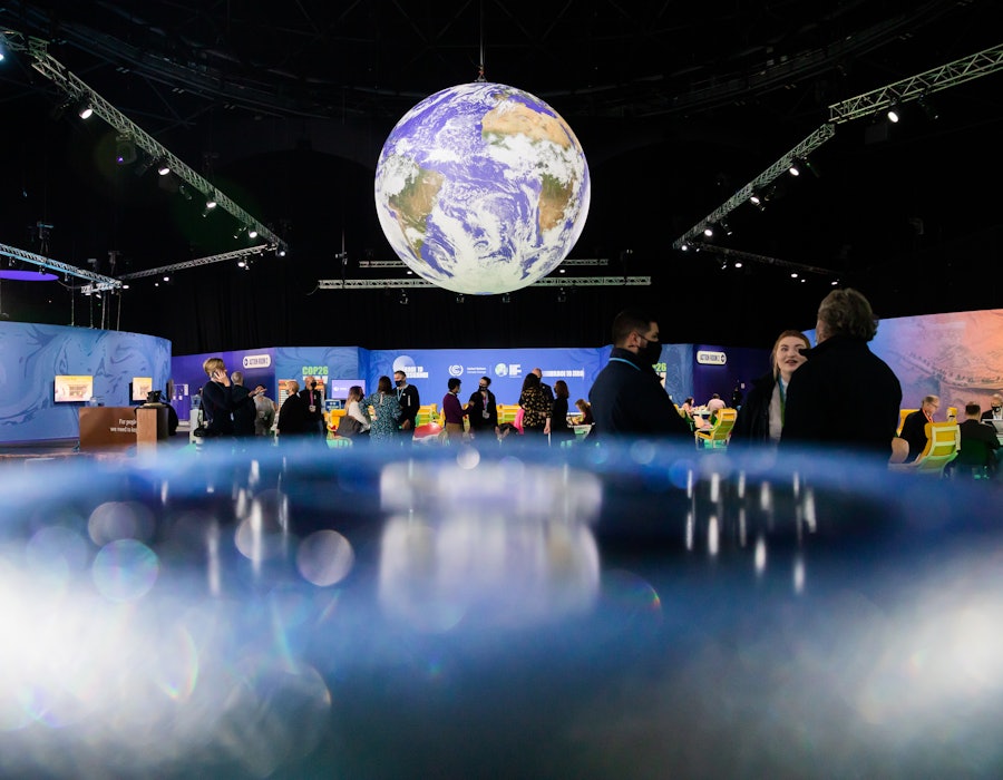 People are standing under a globe at the UN Climate Change Conference COP26. For two weeks in Glasgo...