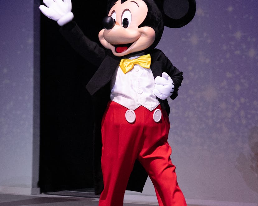 Image of a costumed Mickey Mouse character walking and waving hello.