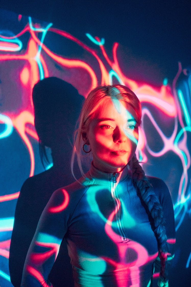 Young woman standing in front of colorful projector light, thinking about how the December 2021 full...