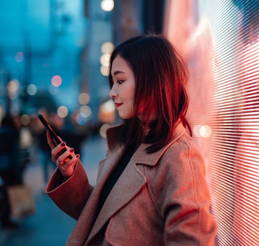 Young woman reading phone in the street, thinking about how the December 2021 full moon in Gemini 20...