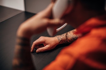 One man, male prisoner sitting in prison visit room, talking on phone.