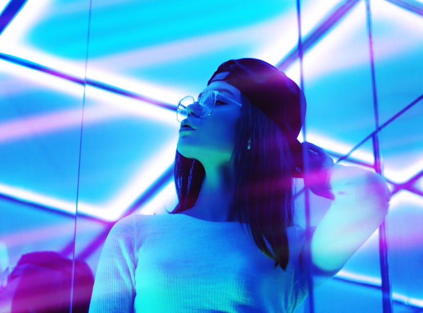 Young woman surrounded by blue neon light, thinking about how the December 2021 full moon in Gemini ...