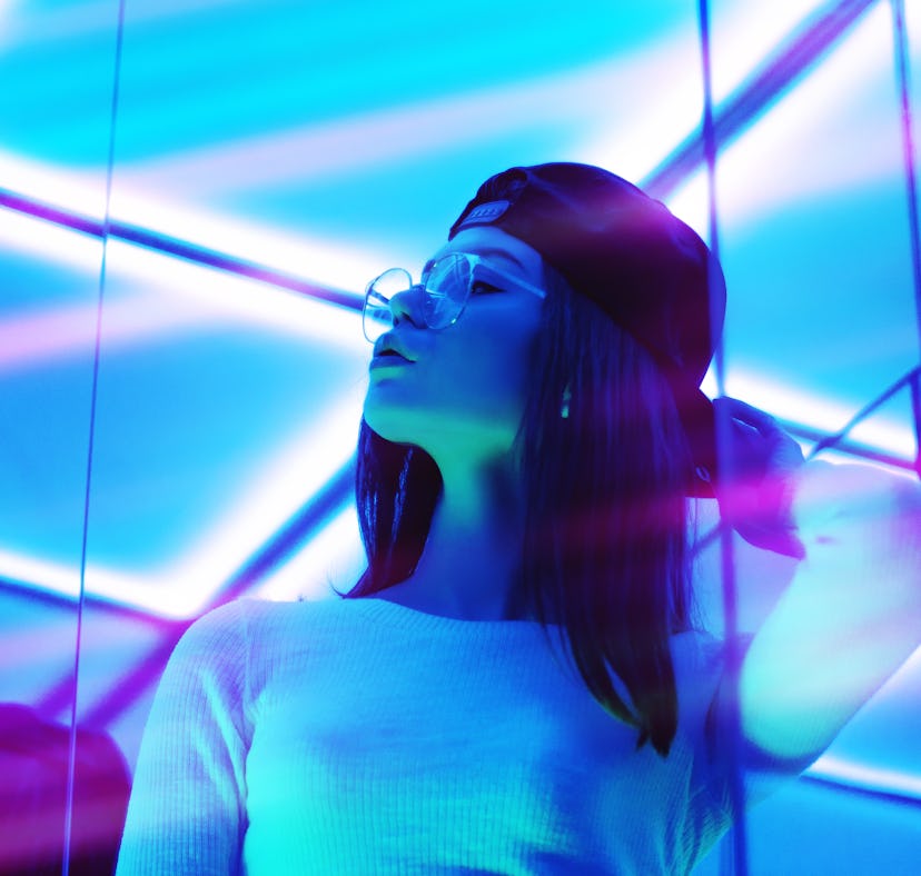 Young woman surrounded by blue neon light, thinking about how the December 2021 full moon in Gemini ...