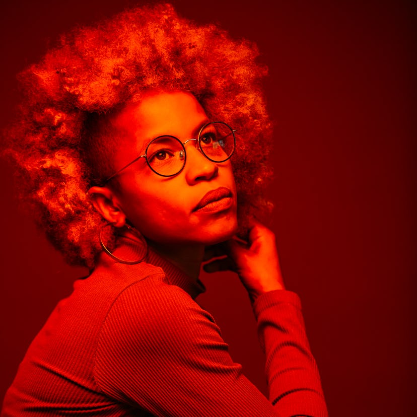 young woman lit by a red light reflects on her north node in scorpio