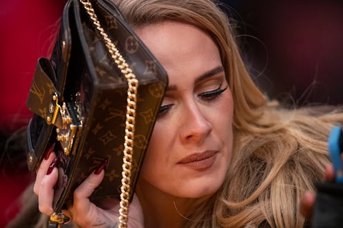 Los Angeles, CA - October 19: Singer Adele uses her purse to hide from the TV camera while she sings...
