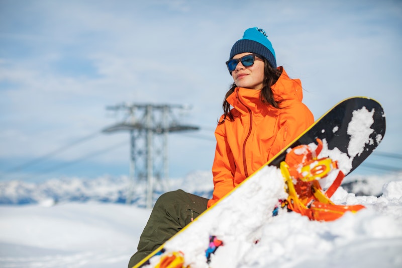 A woman sits while snowboarding. Here's your horoscope for sagittarius season 2021.