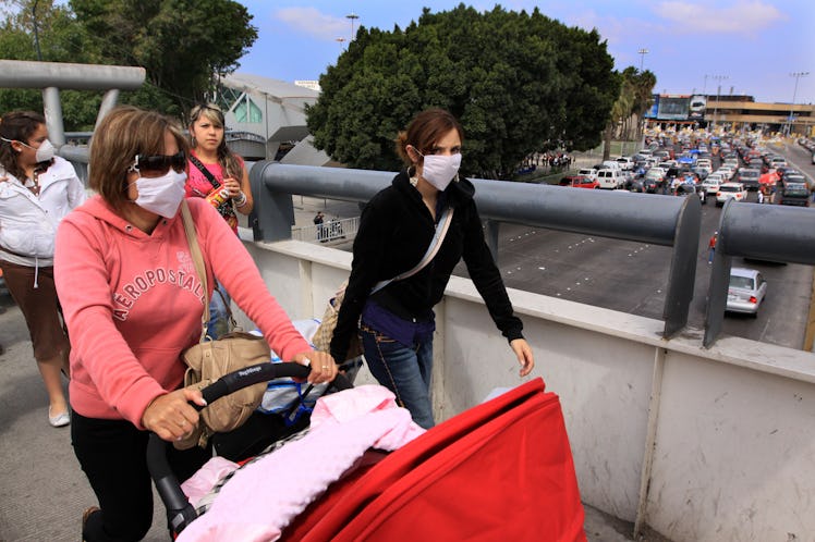 Pedestrians head towards the U.S-Mexico border Port of Entry in Tijuana, Mexico.  The World Health O...