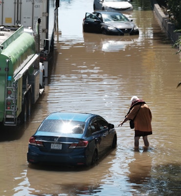 NEW YORK, NY - SEPTEMBER 02: A person walks next to an abandoned car on the flooded Major Deegan Exp...