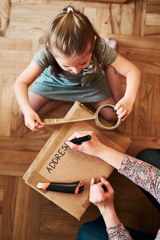 Photo of child and adult wrapping a box to ship in the mail. 