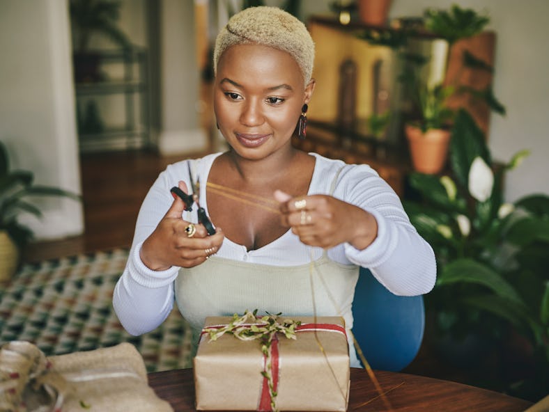 A woman decorating her home and wrapping presents with the 2021 holiday home decor trends.
