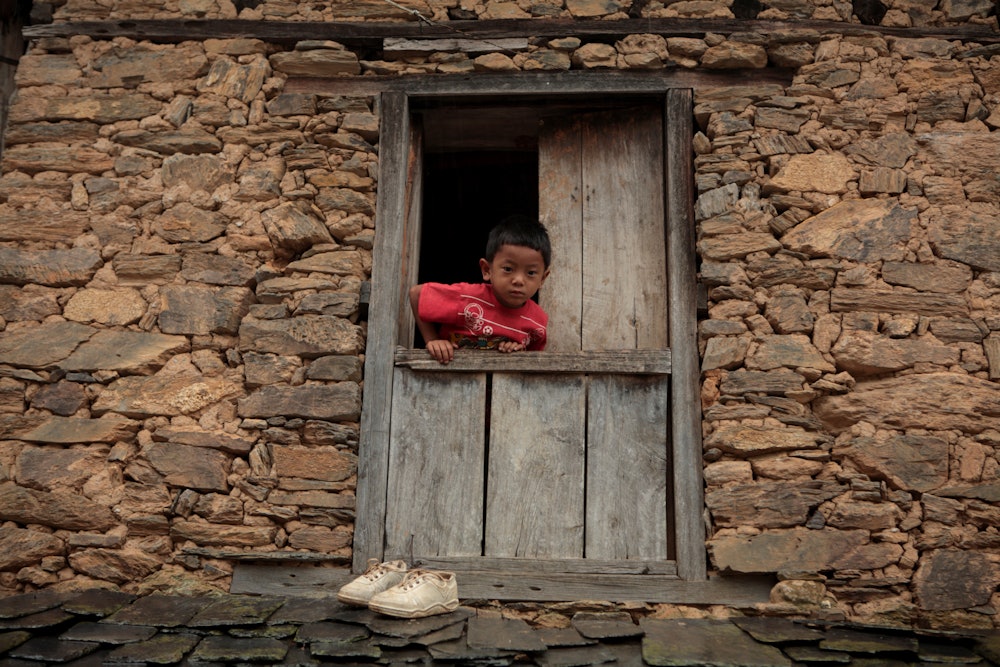 A child looks out of the window of his home, in Bandipur, Nepal. June 26, 2010. Bandipur is a hillto...