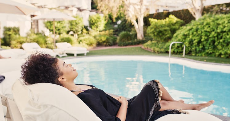 A woman lounges by a pool on vacation using a Black Friday 2021 travel deal. 